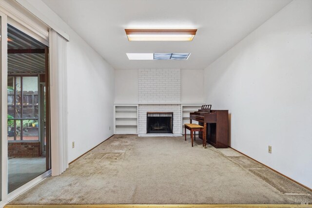 living room featuring a skylight, carpet, and a brick fireplace