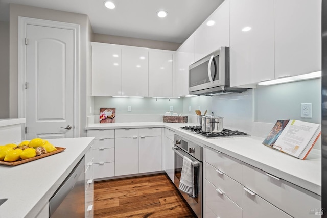 kitchen with stainless steel appliances, dark wood-type flooring, and white cabinets