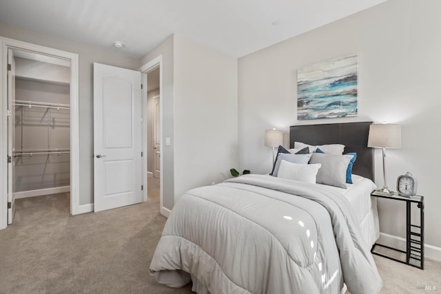 carpeted bedroom with a walk in closet and a closet