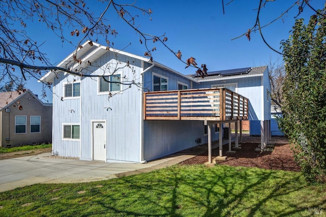 back of house with a yard, a deck, and solar panels