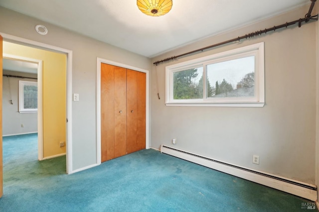 unfurnished bedroom featuring a baseboard heating unit, a closet, and carpet flooring