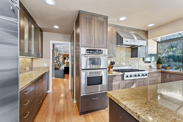 3057 Saint Helena Hwy N, Saint Helena, CA 94574 - kitchen with stainless steel appliances, wall chimney exhaust hood, light wood-style flooring, light stone countertops, and backsplash