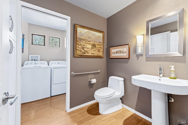 bathroom with hardwood / wood-style flooring, independent washer and dryer, toilet, and sink