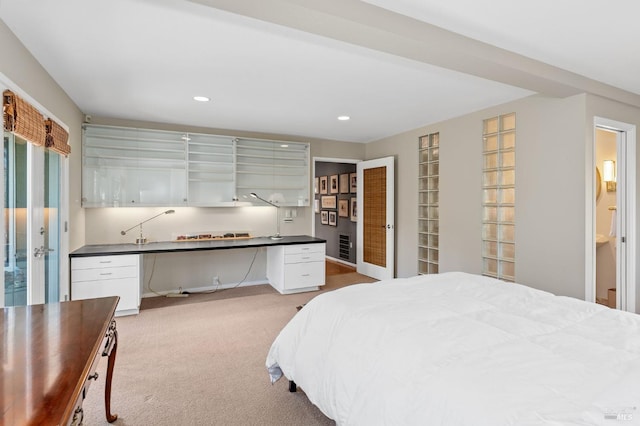 bedroom featuring ensuite bathroom, built in desk, and light colored carpet