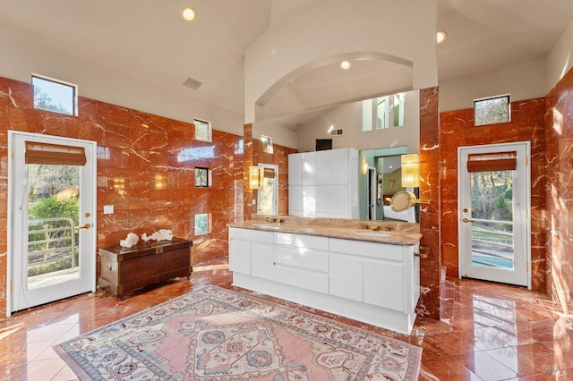 kitchen featuring white cabinetry, plenty of natural light, high vaulted ceiling, and tile walls