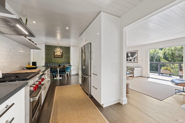 kitchen featuring white cabinetry, hanging light fixtures, stainless steel appliances, tasteful backsplash, and extractor fan