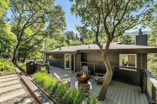 back of property with a wooden deck and an outdoor fire pit