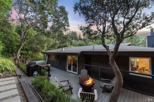 back house at dusk with a deck and an outdoor fire pit