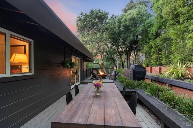 deck at dusk featuring a fire pit and grilling area