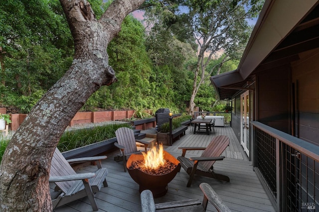 deck at dusk with grilling area and an outdoor fire pit