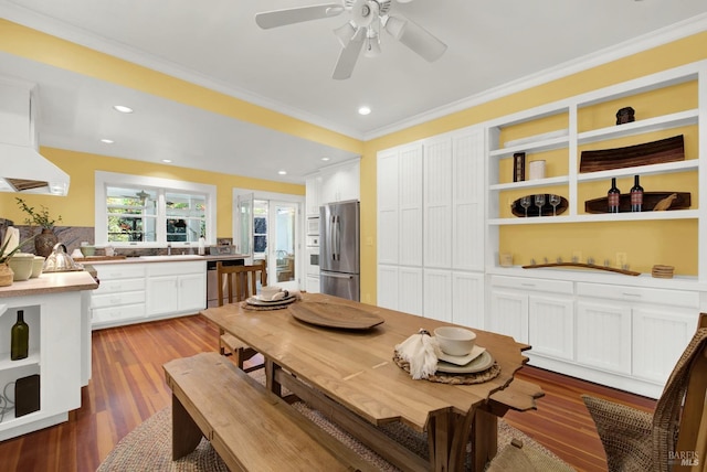 dining space featuring hardwood / wood-style flooring, ornamental molding, built in shelves, and ceiling fan