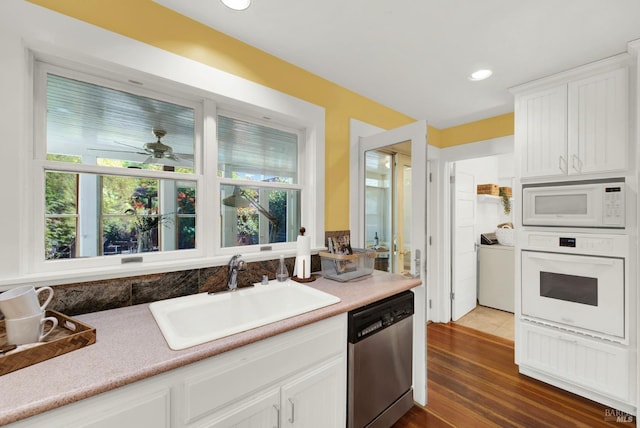 kitchen featuring dark wood-type flooring, sink, white appliances, washer / clothes dryer, and white cabinets