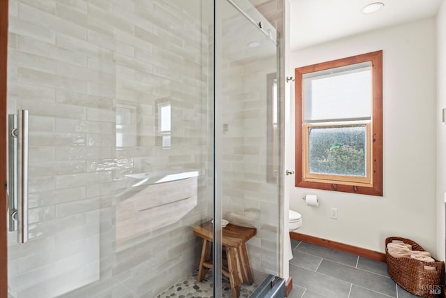 bathroom with tile patterned floors, toilet, and a shower with door