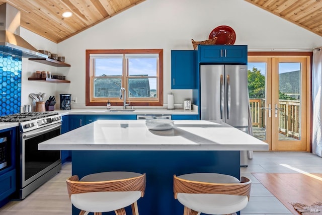 kitchen with sink, a center island, exhaust hood, stainless steel appliances, and blue cabinetry