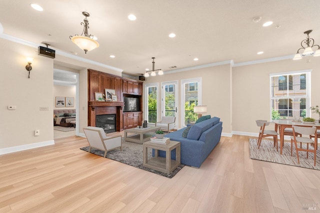 living room featuring crown molding, recessed lighting, light wood-style floors, a glass covered fireplace, and baseboards