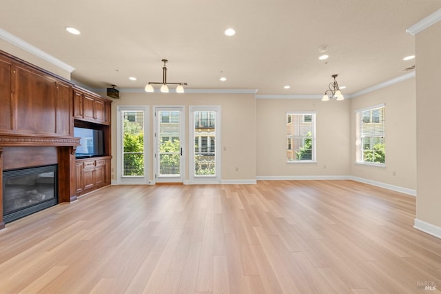 unfurnished living room with baseboards, ornamental molding, a glass covered fireplace, and light wood-style floors