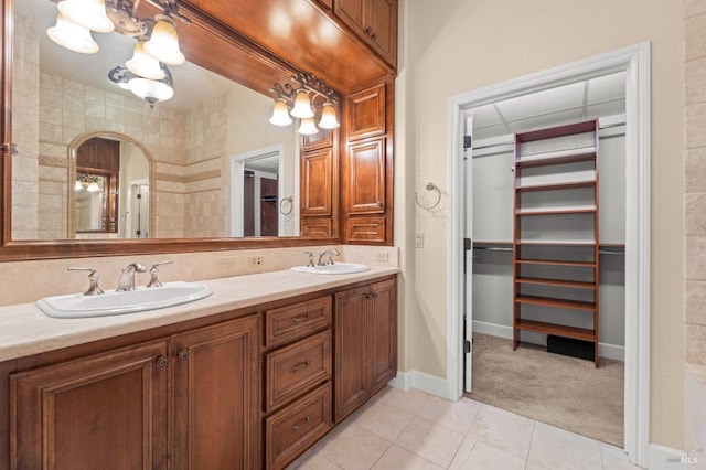 bathroom featuring double vanity, a sink, a walk in closet, and tile patterned floors