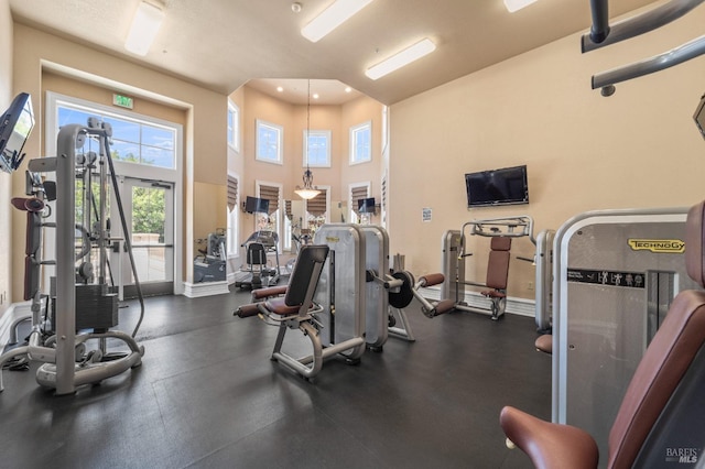 gym featuring recessed lighting, a towering ceiling, and baseboards