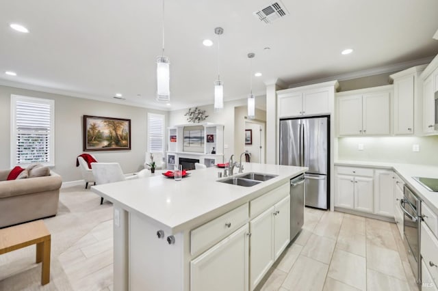 kitchen featuring sink, a kitchen island with sink, white cabinetry, hanging light fixtures, and stainless steel appliances