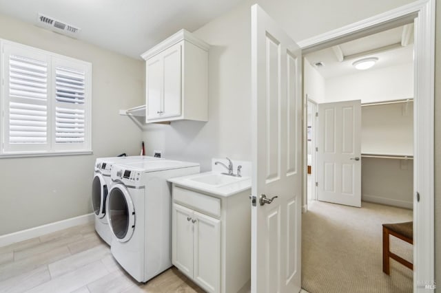 clothes washing area with independent washer and dryer, cabinets, and sink