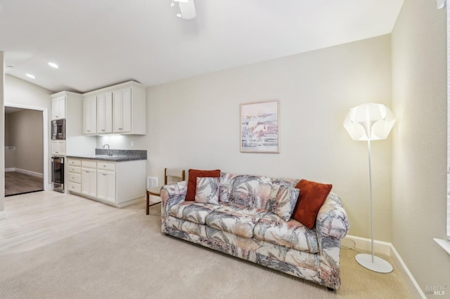 carpeted living room with ceiling fan, sink, and vaulted ceiling