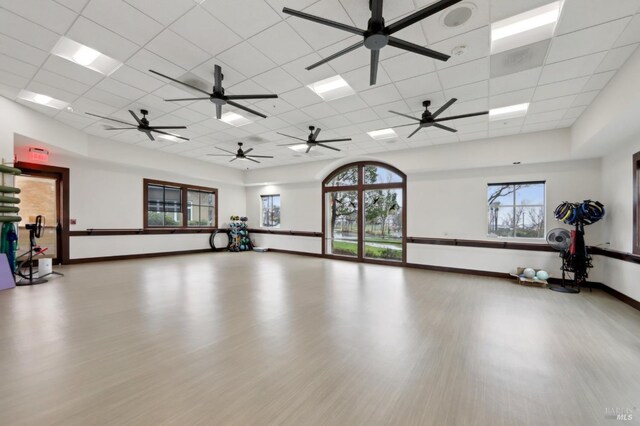 workout room with a healthy amount of sunlight, a paneled ceiling, and light hardwood / wood-style flooring