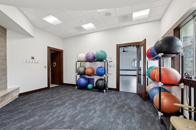 workout room with a drop ceiling, dark carpet, and a wealth of natural light