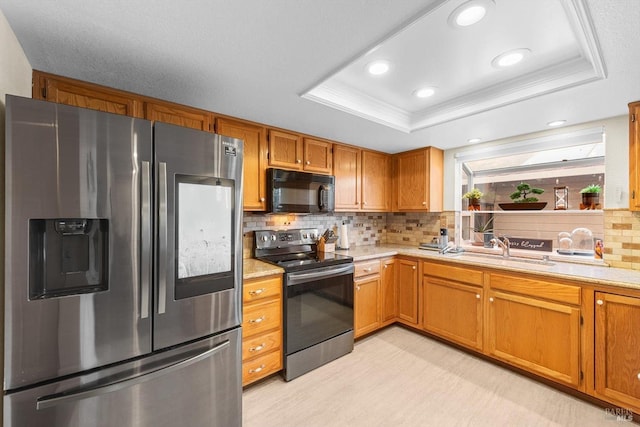 kitchen featuring sink, crown molding, appliances with stainless steel finishes, tasteful backsplash, and a tray ceiling