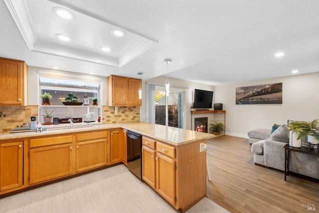 kitchen featuring a fireplace, black dishwasher, kitchen peninsula, a raised ceiling, and crown molding