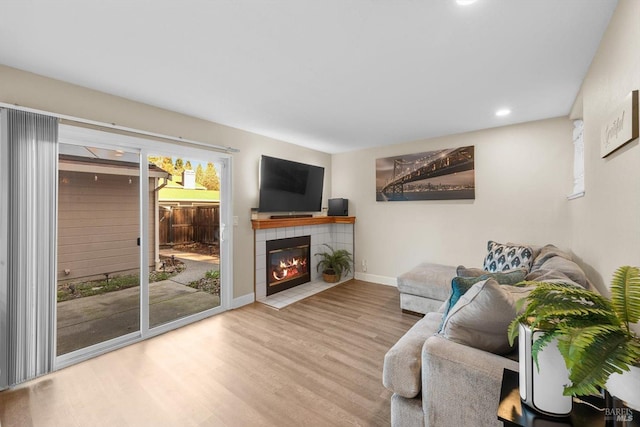 living room with a tiled fireplace and light hardwood / wood-style floors