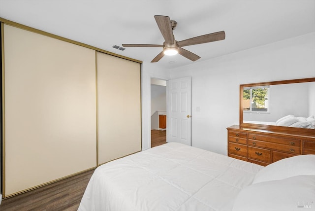 bedroom with ceiling fan, dark hardwood / wood-style flooring, and a closet