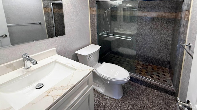 bathroom with vanity, toilet, and tiled shower