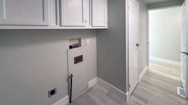 clothes washing area with cabinets, washer hookup, hookup for an electric dryer, and light wood-type flooring