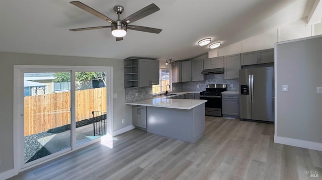 kitchen with lofted ceiling, decorative backsplash, kitchen peninsula, stainless steel appliances, and a healthy amount of sunlight