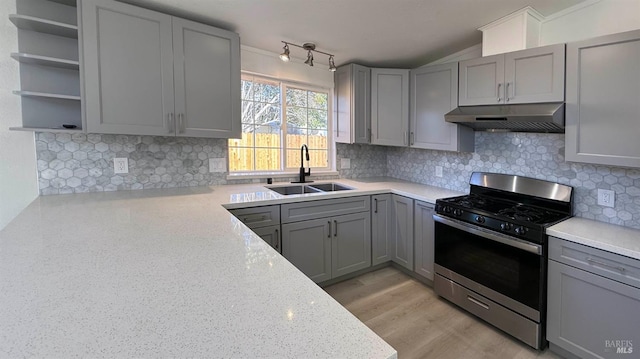 kitchen with gray cabinets, gas stove, light stone countertops, and sink