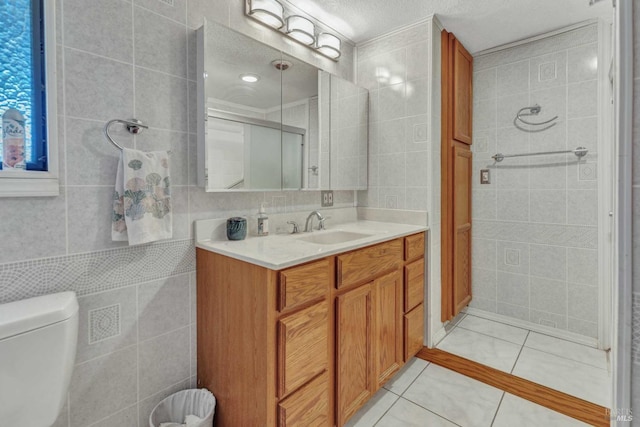 bathroom with tile walls, toilet, a textured ceiling, vanity, and tile patterned flooring