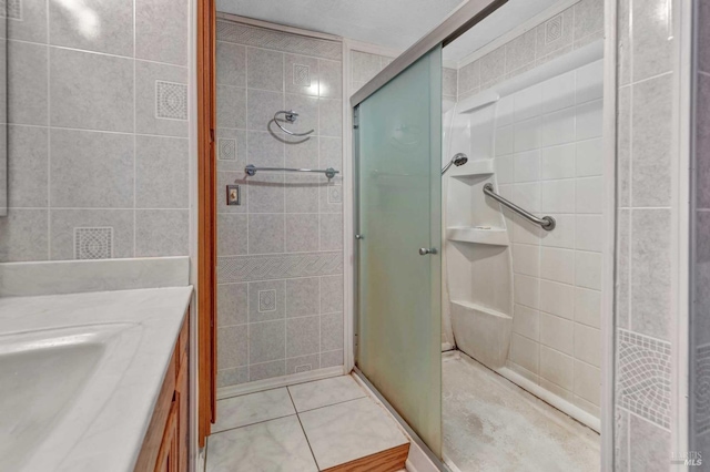 full bathroom featuring tile walls, a shower stall, vanity, and tile patterned floors