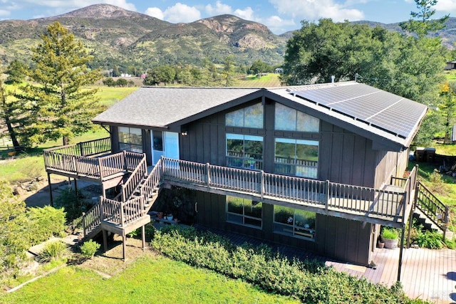 view of front of property with a deck with mountain view, stairway, solar panels, and board and batten siding