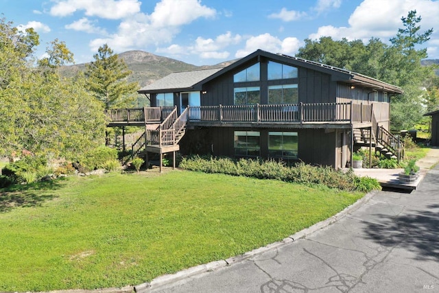 rustic home featuring a deck with mountain view, a front lawn, and stairway