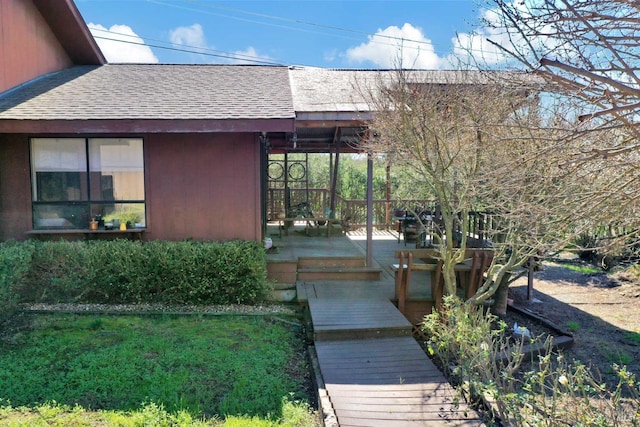 doorway to property with a shingled roof and a yard