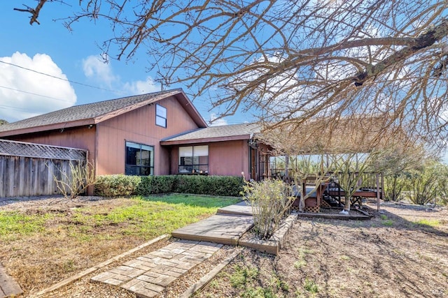 exterior space featuring fence, a front lawn, and roof with shingles