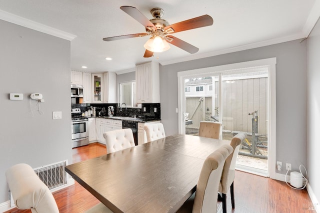 dining space featuring ornamental molding, sink, ceiling fan, and light hardwood / wood-style flooring