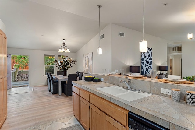 kitchen with sink, dishwasher, an inviting chandelier, decorative light fixtures, and vaulted ceiling