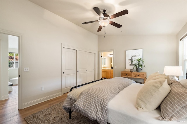 bedroom with hardwood / wood-style floors, lofted ceiling, ceiling fan, ensuite bath, and a closet