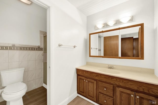 bathroom featuring vanity, toilet, hardwood / wood-style floors, and tile walls