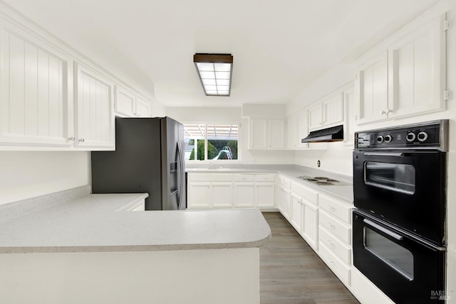 kitchen with double oven, white cabinetry, white cooktop, stainless steel fridge, and dark hardwood / wood-style flooring