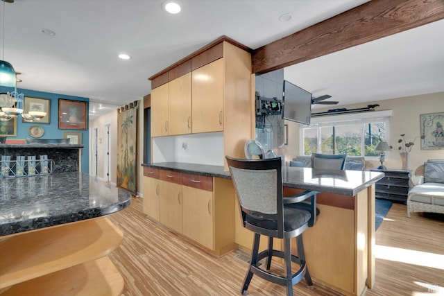 kitchen with a breakfast bar area, ceiling fan, light brown cabinets, decorative light fixtures, and light wood-type flooring