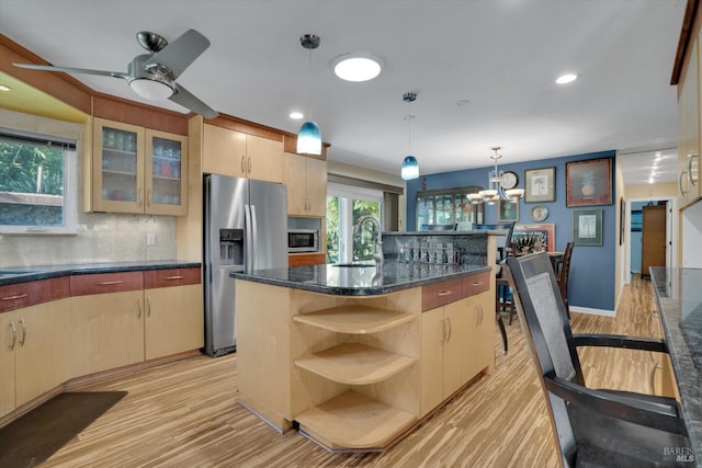 kitchen featuring pendant lighting, sink, appliances with stainless steel finishes, a center island with sink, and light brown cabinetry