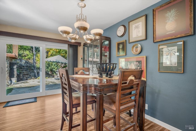 dining area with light hardwood / wood-style floors and a notable chandelier