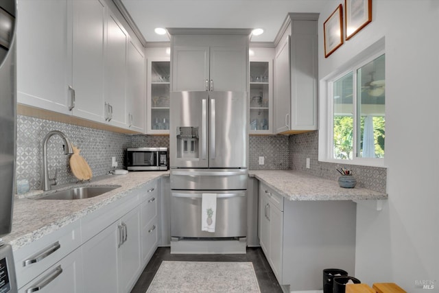 kitchen with sink, white cabinets, decorative backsplash, light stone counters, and stainless steel appliances